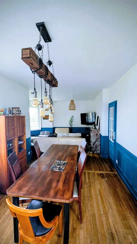 Salle à manger terminée avec murs blancs, soubassements bleu foncé et plafond clair.
