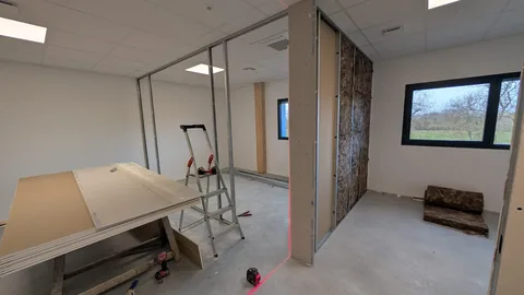 Cloison en cours de montage sur ossature métallique avec panneaux isolants visibles.