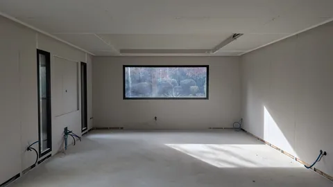 Pièce vide doublée de plaques de plâtre aux murs et au plafond, avec vis et joints visibles.