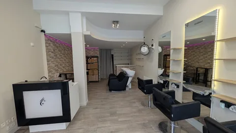 Salon de coiffure aménagé sous un faux plafond courbe blanc avec éclairages encastrés.