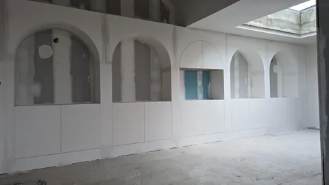 Grand mur en plaques de plâtre avec cinq niches cintrées et rangements bas intégrés.